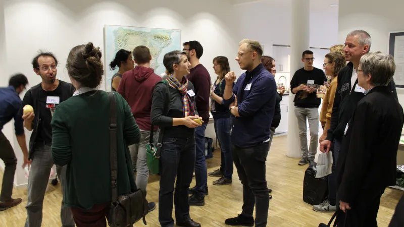 In einem hellen Veranstaltungsort stehen viele Menschen mit Namensschildern und unterhalten sich angeregt.