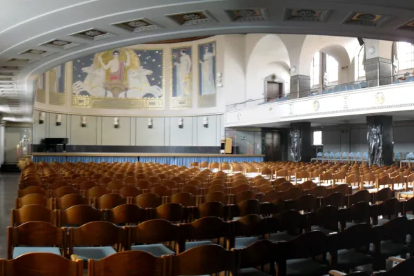 A large, round, seated hall in the Art Nouveau style with raised tiers and a stage.