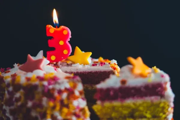 birthday cake with a burning candle on top in the shape of a 3