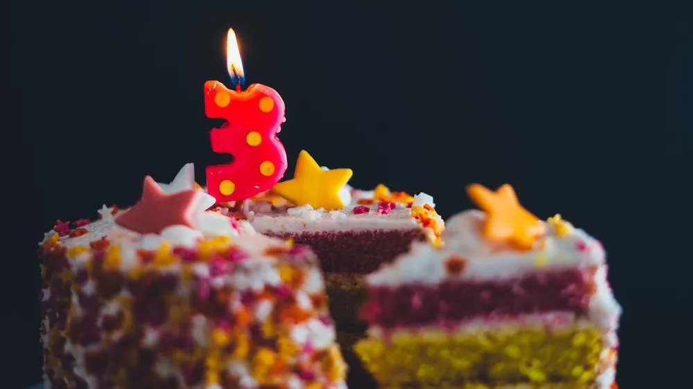 birthday cake with a burning candle on top in the shape of a 3