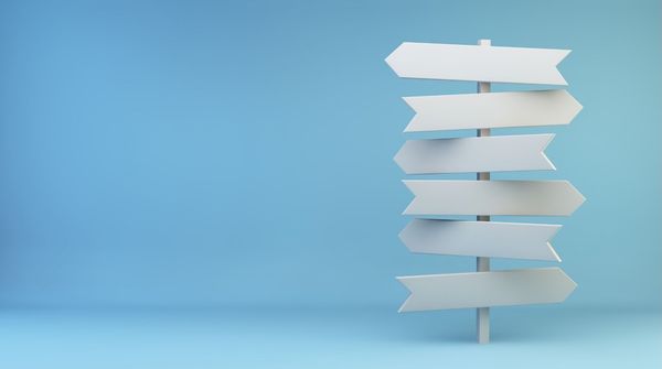 Das Bild zeigt einen weißen Wegweiser vor einem blauen Hintergrund.