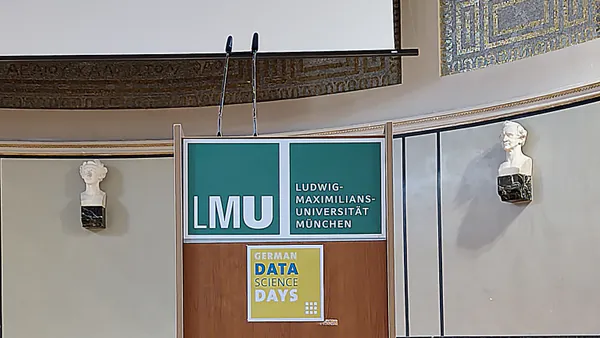Lectern with LMU and German Data Science Days signage, flanked by two classical busts on the auditorium wall.