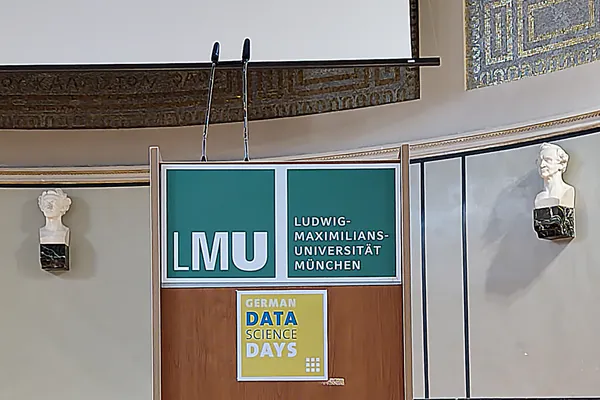 Lectern with LMU and German Data Science Days signage, flanked by two classical busts on the auditorium wall.