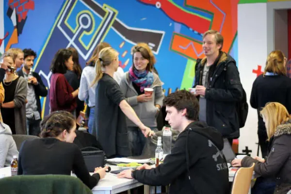 Eine Momentaufnahme des Meet Ups. Einige Personen sitzen, andere stehen. Sie unterhalten sich und die Stimmung ist locker.