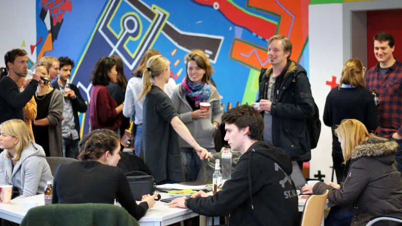 Eine Momentaufnahme des Meet Ups. Einige Personen sitzen, andere stehen. Sie unterhalten sich und die Stimmung ist locker.